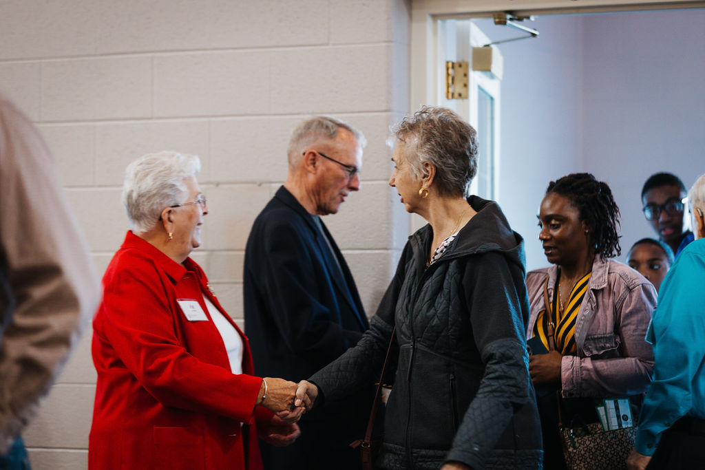 People entering the building, shaking hands and smiling